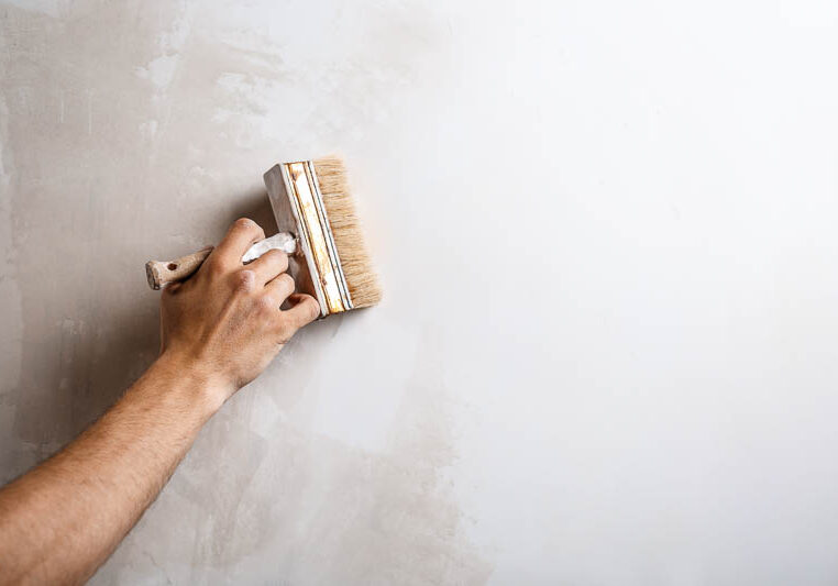 close-up-hand-painting-wall-with-brush