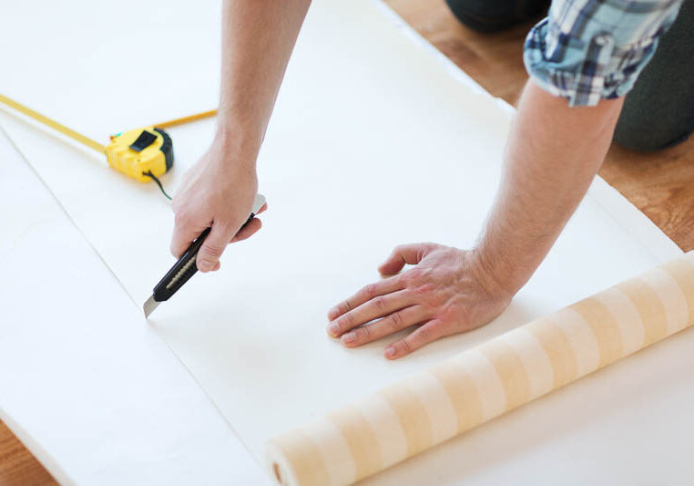 repair-building-home-concept-close-up-male-hands-cutting-wallpaper